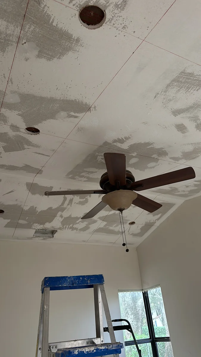 Ceiling drywall seams and patches mudded before painting, with ceiling fan