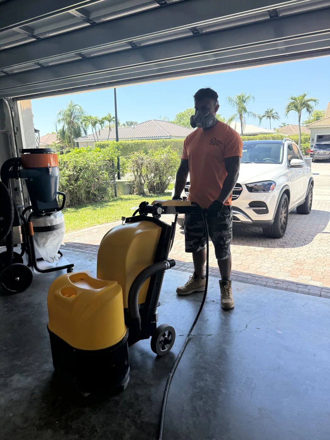 Home Xperts 360 installer with a diamond grinder and dust extractor in a garage