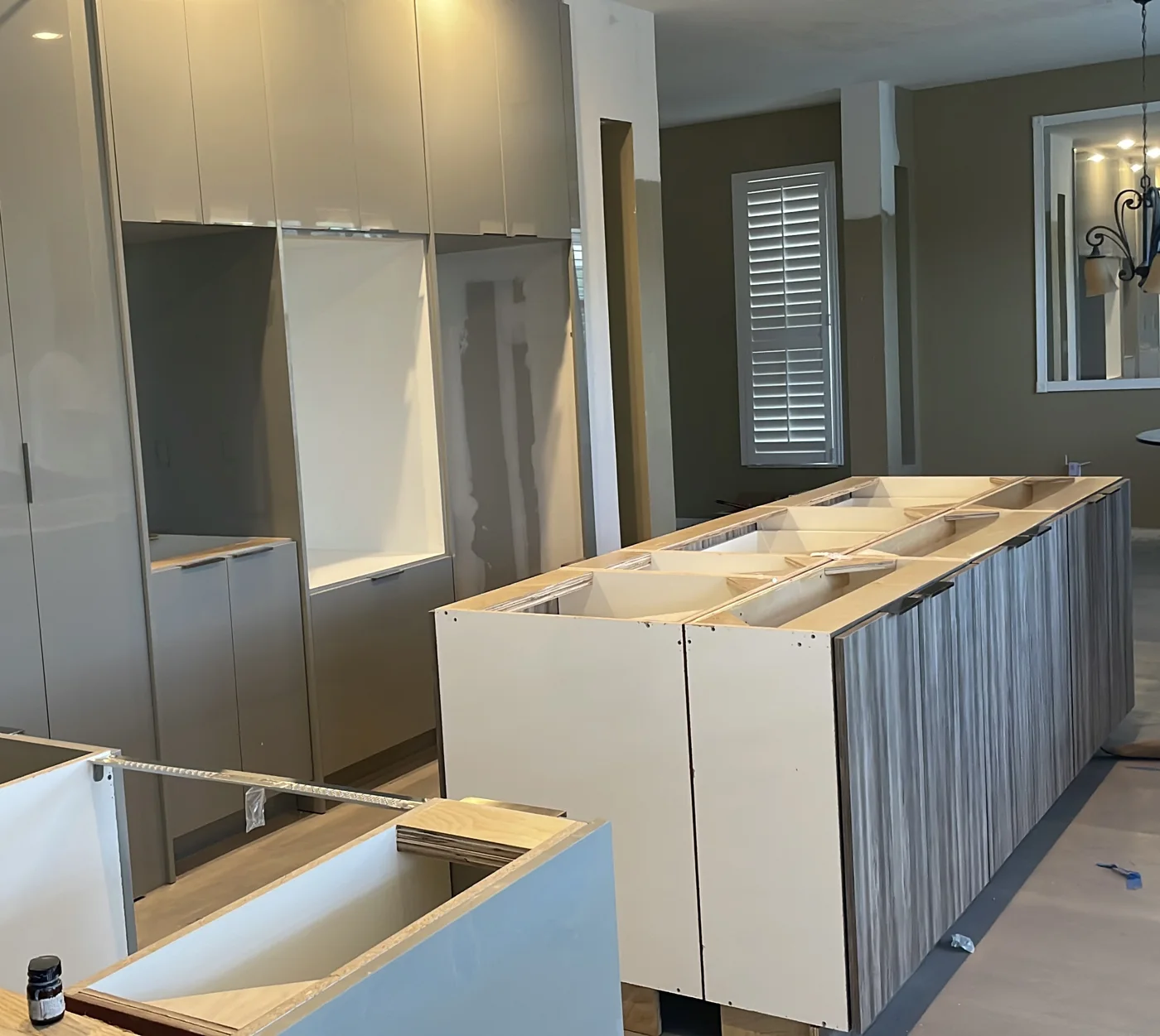 Modern gloss and wood-grain kitchen cabinets and island during installation